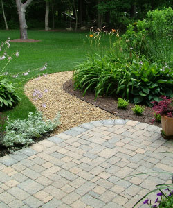 A well-landscaped yard featuring gravel and paving stone walkways.