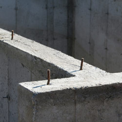 A close-up of a fresh concrete foundation with rebar sticking out.